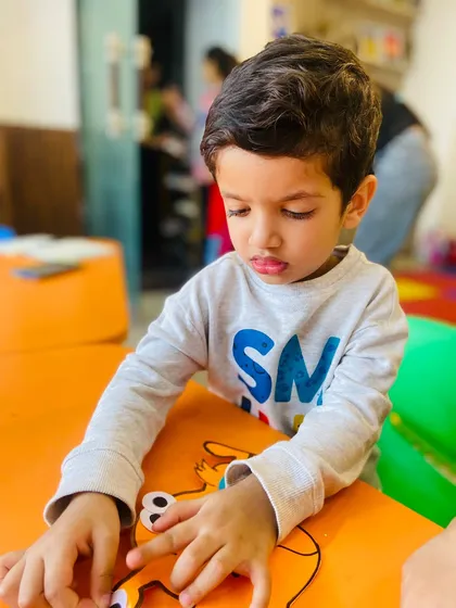 A student is deeply engaged in assembling a craft project. This quiet, focused activity is great for developing fine motor skills and patience.