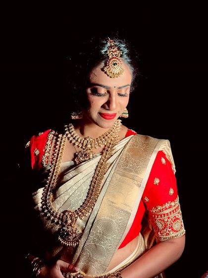 A close-up portrait of Anusha, showcasing her classic red lip and the flawless finish of her airbrush makeup.