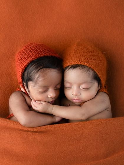 What secrets are they sharing? This playful shot of newborn twins captures a moment of connection, with one appearing to whisper to the other.