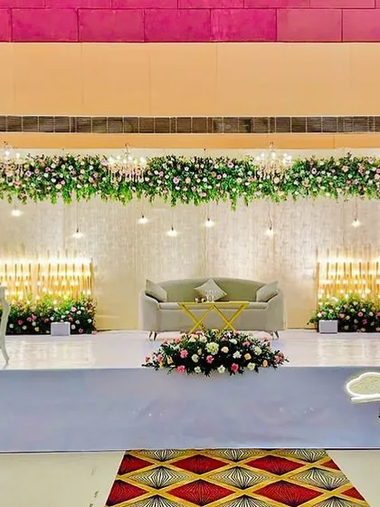 A simple yet beautiful reception stage with a focus on lighting. The warm, cascading lights behind the main seating area, combined with a floral header, create a cozy and inviting glow.