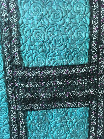 A detailed shot of the swirling rose quilting pattern on the turquoise saree quilt, demonstrating how we use thread to complement the fabric's design.