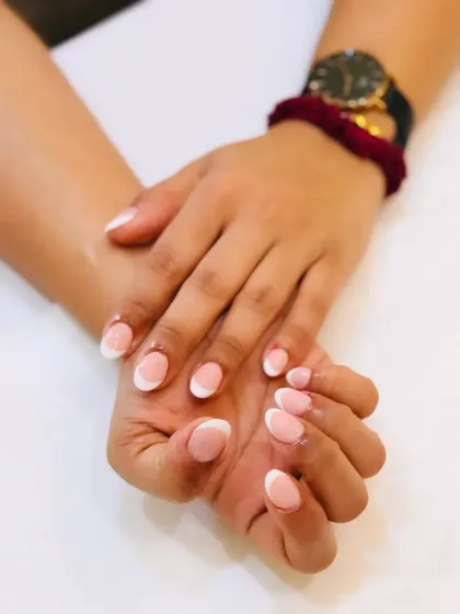 A classic French manicure done right. This photo showcases perfectly shaped, rounded nails with clean white tips and a glossy finish for a look that is always in style.