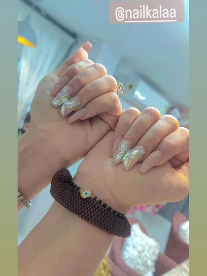 A chic and glamorous design featuring a nude base on square-shaped nails with stunning, fully-crystallized 3D butterfly accents.