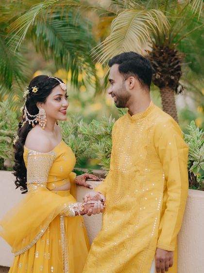 A sweet portrait of the couple holding hands during their Haldi ceremony, dressed in coordinated yellow outfits.