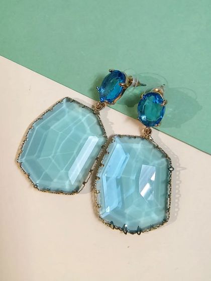 A clean, top-down shot of the aqua blue designer gold-plated crystal earrings.