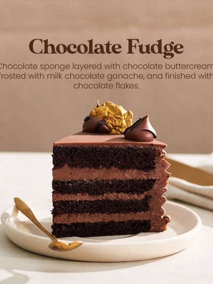 A single, perfect slice of my Chocolate Fudge Cake. This image highlights the four layers of sponge and buttercream, crowned with a chocolate kiss and gold leaf.