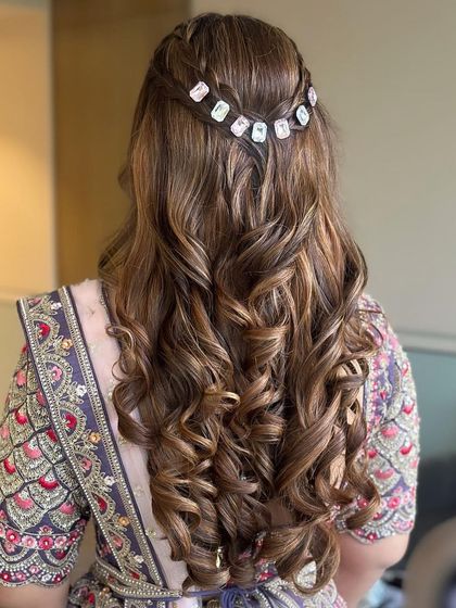 The back of the hairstyle, featuring a braided detail adorned with sparkling stone accessories. This adds a touch of glamour to the curly half-updo.