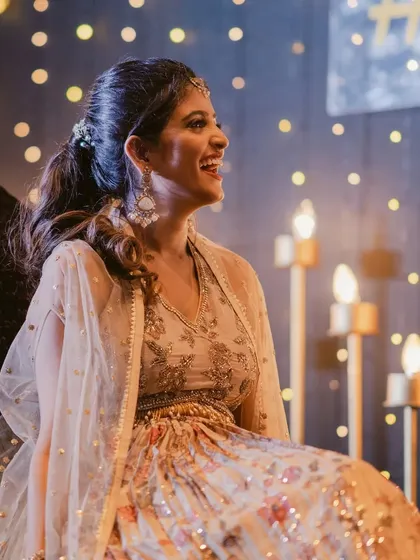 Seated amidst the beautiful sangeet decor, the bride's makeup glows. The warm lighting highlights the radiant finish of her skin and the soft tones of her look.