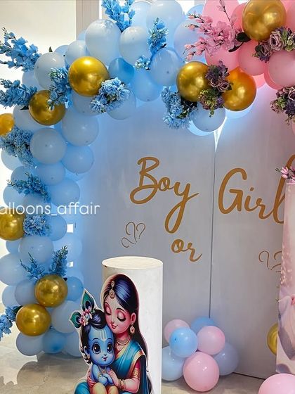 A detailed shot of the gender reveal setup, focusing on the 'Boy or Girl' text and the intricate balloon and floral arrangements.