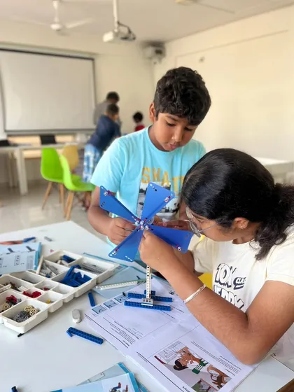 We love seeing our students collaborate and learn from each other. Two young engineers are working together to build a wind-powered machine, learning about gears and energy transfer during our hands-on summer camp.