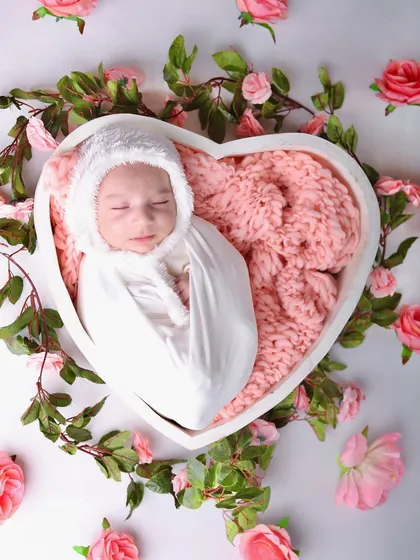 A top-down view of the baby nestled in the heart bowl, encircled by a ring of beautiful pink roses and green leaves.