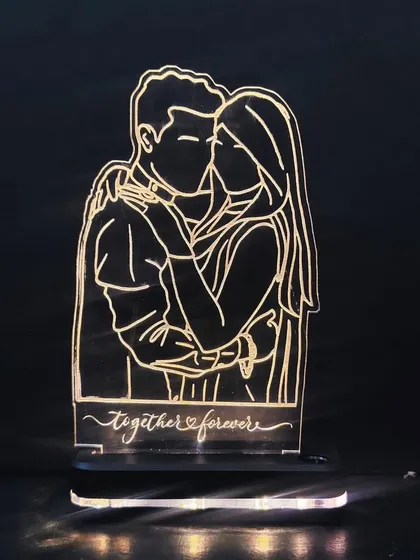 The wireless LED sketch lamp shown in the dark. The warm light beautifully illuminates the custom "Together Forever" message and the couple's portrait.