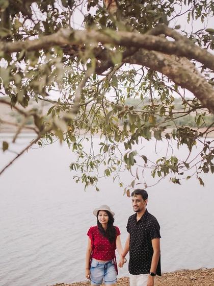 A peaceful walk by the lake. The framing of the shot under a large tree branch gives this pre-wedding photo a natural, documentary-style feel.