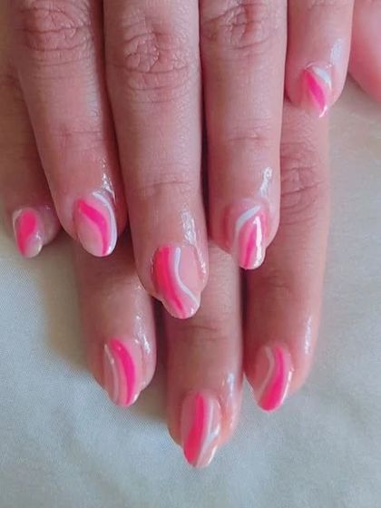 A different angle of the abstract pink and white swirl design on almond-shaped nails.