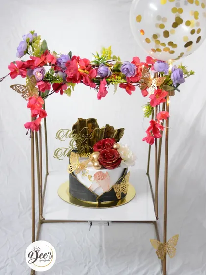 Creating a complete gift experience for an engagement or anniversary. This hamper features an elegant cake set under a floral arch with a confetti balloon, designed to be the centerpiece of any celebration.