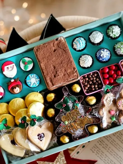 An overhead view of my large Christmas hamper, showcasing the variety of treats inside. You can see the themed cupcakes, gingerbread men, assorted cookies, and chocolates, all artfully arranged.