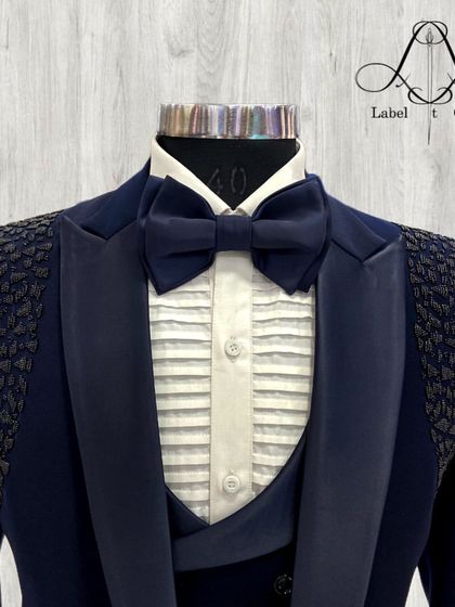 A closer view of the navy blue tuxedo, focusing on the pleated shirt, satin bow tie, and the detailed shoulder work. This highlights how I balance classic elements with personalized, modern touches.