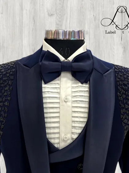 A close-up of the navy tuxedo, highlighting the pleated shirt, satin lapels, and the unique texture on the shoulders. It's a true work of art.
