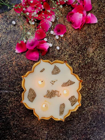 A lit mini gold Urli candle, its multiple wicks creating a beautiful, warm glow.