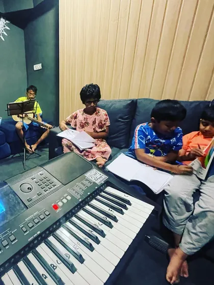 A typical learning session in our studio. Here, students are engaged in reading music and practicing their instruments, including keyboard and guitar, in a comfortable group setting.