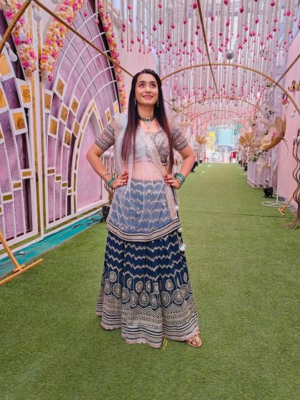 A client posing in a navy blue printed lehenga with a sheer dupatta. This is a great lightweight option for a sangeet or festive event.