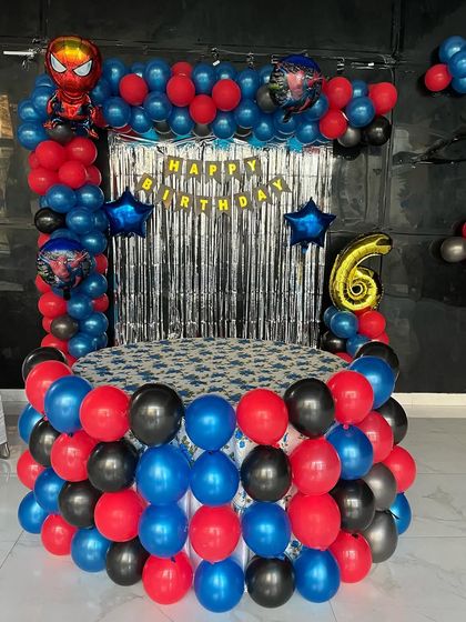 A bold Spiderman theme for a 6th birthday. This decoration surrounds a cake-cutting table with red, blue, and black balloons.