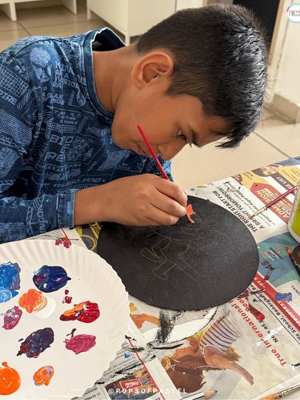 A young boy paints the base design on his coaster before starting the dotting process.