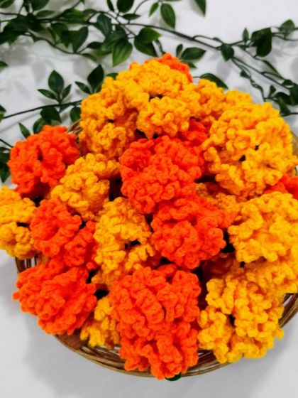 A basket full of bright orange and yellow crochet marigolds from a recent bulk order.