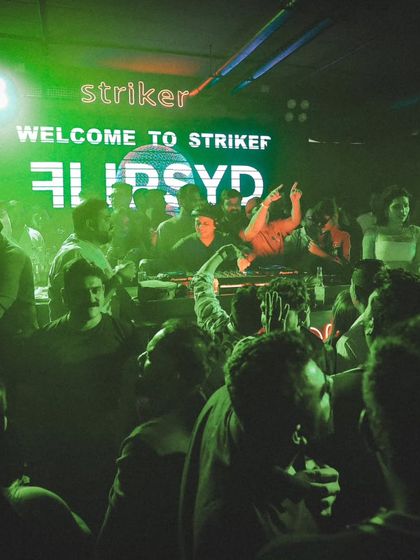 "Welcome to Striker." A green-lit crowd in Indore, fully engaged and ready to party. The energy is visible.