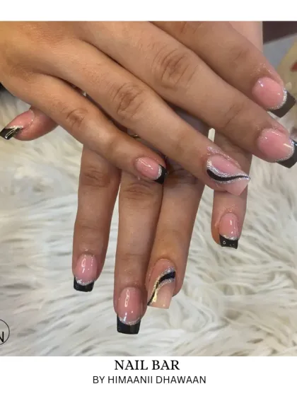 A modern take on the French manicure with sharp, graphic black tips and silver glitter accents.
