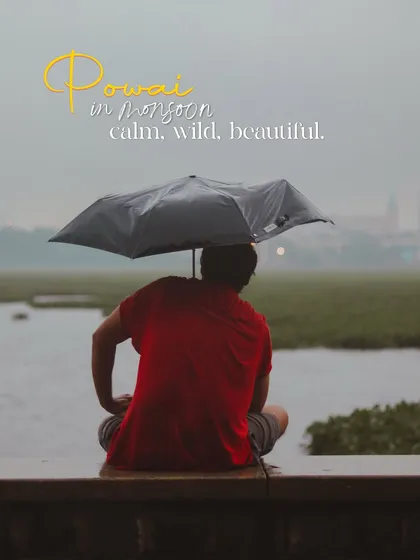 Finding a moment of calm amidst the wild beauty of Powai in monsoon. A lone figure sits by the lake with an umbrella, soaking in the serene, misty atmosphere.