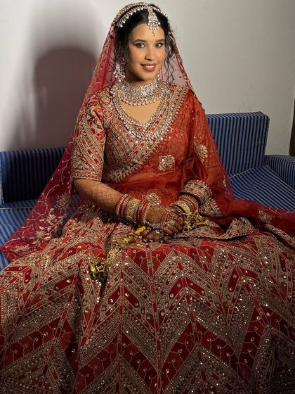 A full-length view of the bride's stunning red lehenga. The makeup is designed to balance the intricate outfit, creating a cohesive and glamorous bridal look.