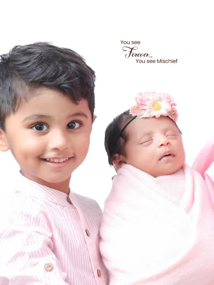A proud big brother poses with his sleeping newborn sister. Sibling photos with a newborn require extra care and patience, which I always provide.