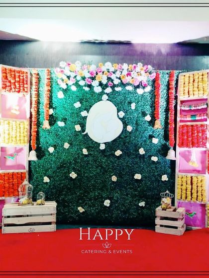 A vibrant backdrop for a naming ceremony or baby shower, featuring a grid of colorful fabrics and marigold flowers. A central Ganesha cutout adds a divine blessing.