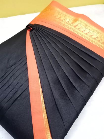 A classic black and orange cotton saree. The pleats are done to perfection, making it a great choice for both work and casual events.