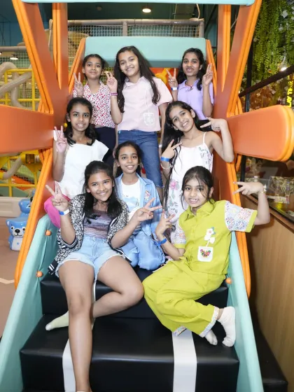 A group of friends poses for a picture on the steps of a slide, capturing a memory from their fun day playing together.
