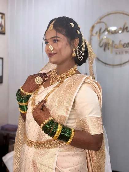 A beautiful Buddhist bride in a traditional white and gold saree, complete with green bangles and a Maharashtrian nath.