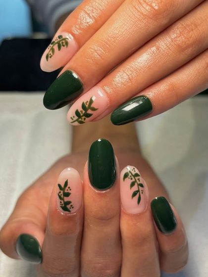 A different perspective on the dark green and leaf-patterned nails, showing the glossy finish and elegant almond shape.