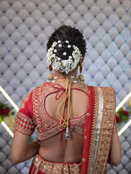 A classic bridal bun decorated with a full gajra of fresh flowers and pearls, a timeless choice for any bride.