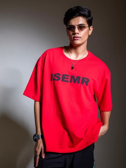 A clean studio portrait of a model in a bright red graphic tee. The focus is on the product, with minimal styling to ensure the brand's design stands out.