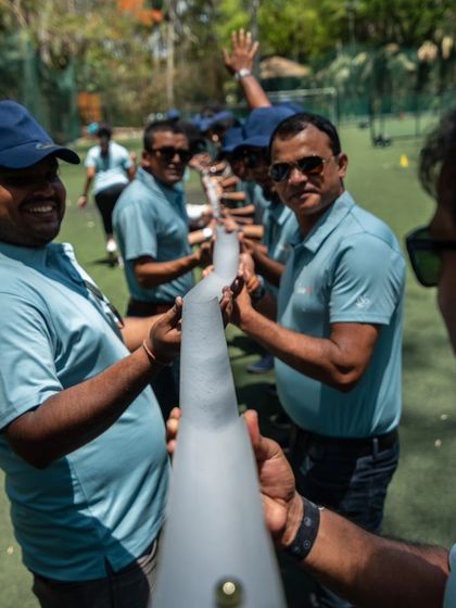 A corporate team working together on the Pipeline challenge, a classic game that tests communication and steady hands.