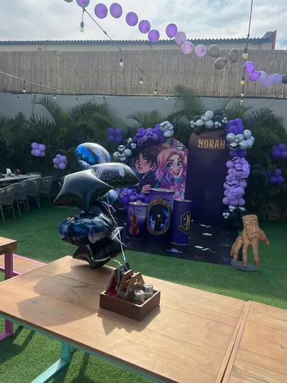 The full outdoor setup for the Wednesday party, including a themed backdrop and "Thing" as a fun prop.