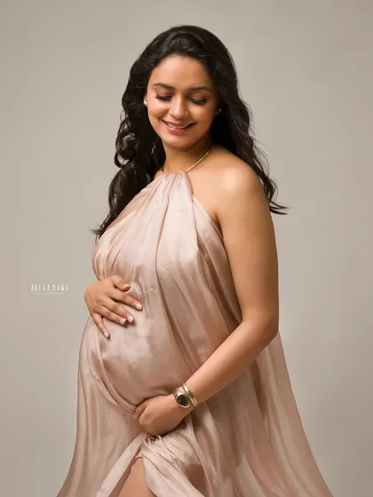 The soft glow of motherhood. This portrait in a rose gold silk gown uses gentle, directional light to create a warm and intimate feel against the dark backdrop.