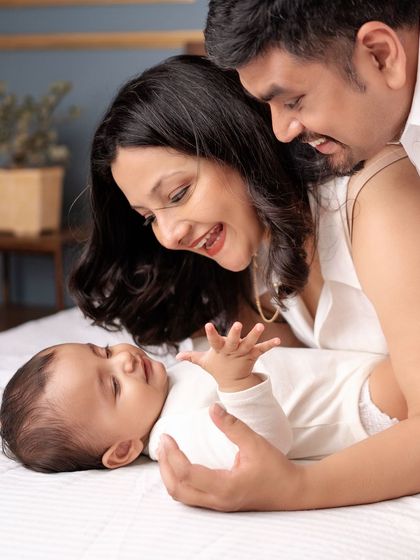 A close-up of a family enjoying a quiet moment with their baby on the bed.