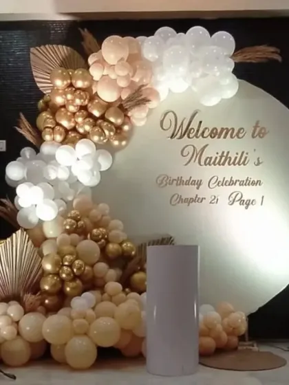 An elegant birthday celebration with a personalized circular backdrop. The setup features a balloon arrangement in cream, white, and gold, with dried pampas grass for a bohemian touch.
