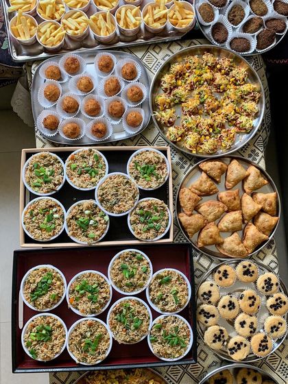 A vibrant party spread with individual portions of veg fried rice, samosas, mini pizzas, and more. This is how I prepare for large party catering orders.