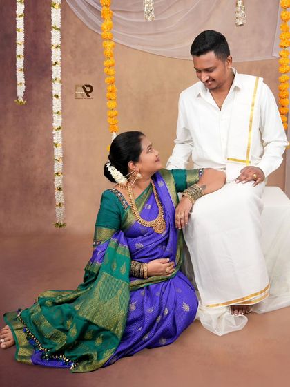 An intimate moment between the couple during their traditional maternity shoot. The rich blue and green saree stands out against the simple, elegant studio setup.