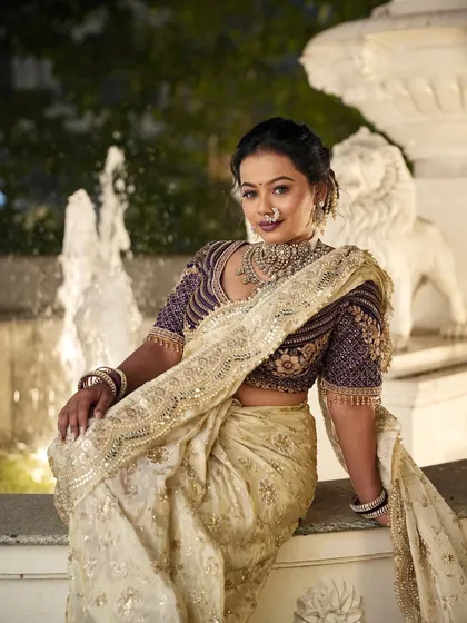 This bride is seated by a fountain, her traditional hairstyle holding perfectly. The updo is adorned with subtle hair accessories that catch the light beautifully.