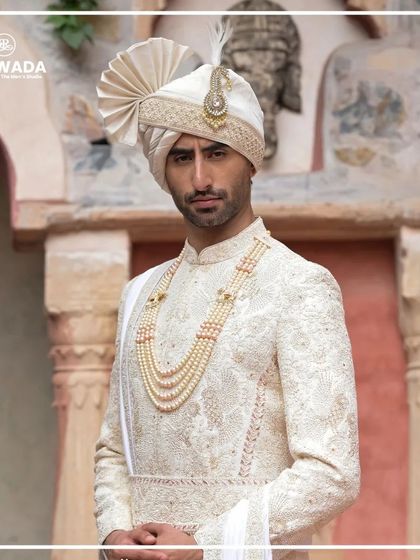 A detailed shot of the groom's sherwani, highlighting the texture of the fabric and the precision of the handwork. This is craftsmanship you can see and feel.