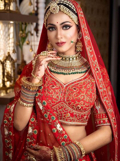 A full view of the bride in her red lehenga, perfectly complemented by our traditional gold-plated Kundan rental set.